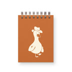 Notebook with a white duck illustration wearing a hat on an orange cover